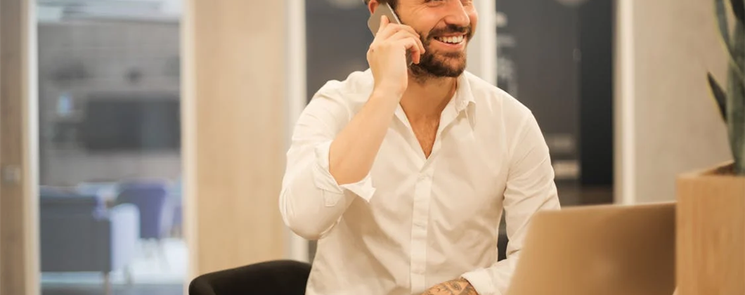 Smiling man with laptop talking on the phone.